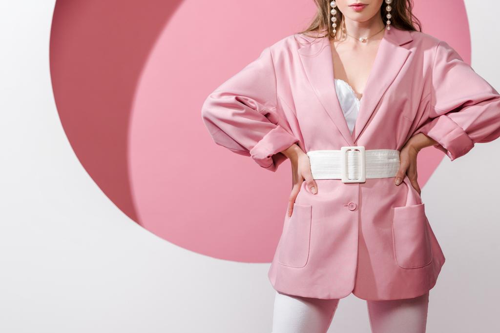 vista ritagliata di donna elegante in piedi con le mani sui fianchi su bianco e rosa
  - Foto, immagini