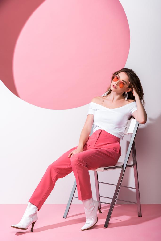donna elegante seduta sulla sedia su rosa e bianco
  - Foto, immagini