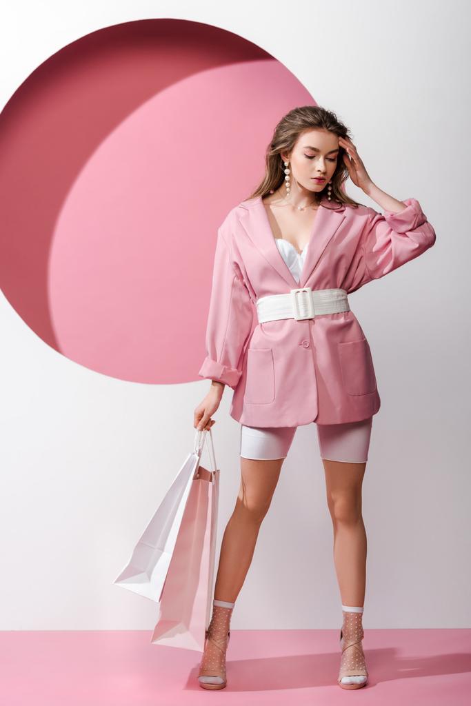 atractiva mujer joven sosteniendo bolsas de compras en blanco y rosa
  - Foto, Imagen
