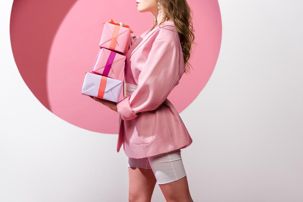 cropped view of woman holding gifts on pink and white  - Photo, Image