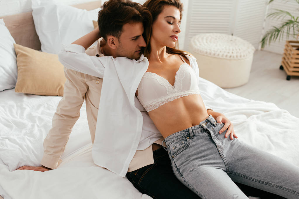 girlfriend in bra hugging and sitting on boyfriend in apartment  - Photo, Image