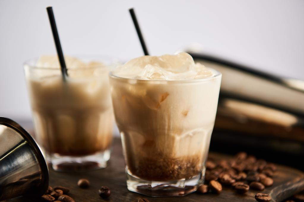 селективный фокус белого русского коктейля в стаканах с соломинками на деревянной доске с зерном кофе, изолированным на сером
 - Фото, изображение