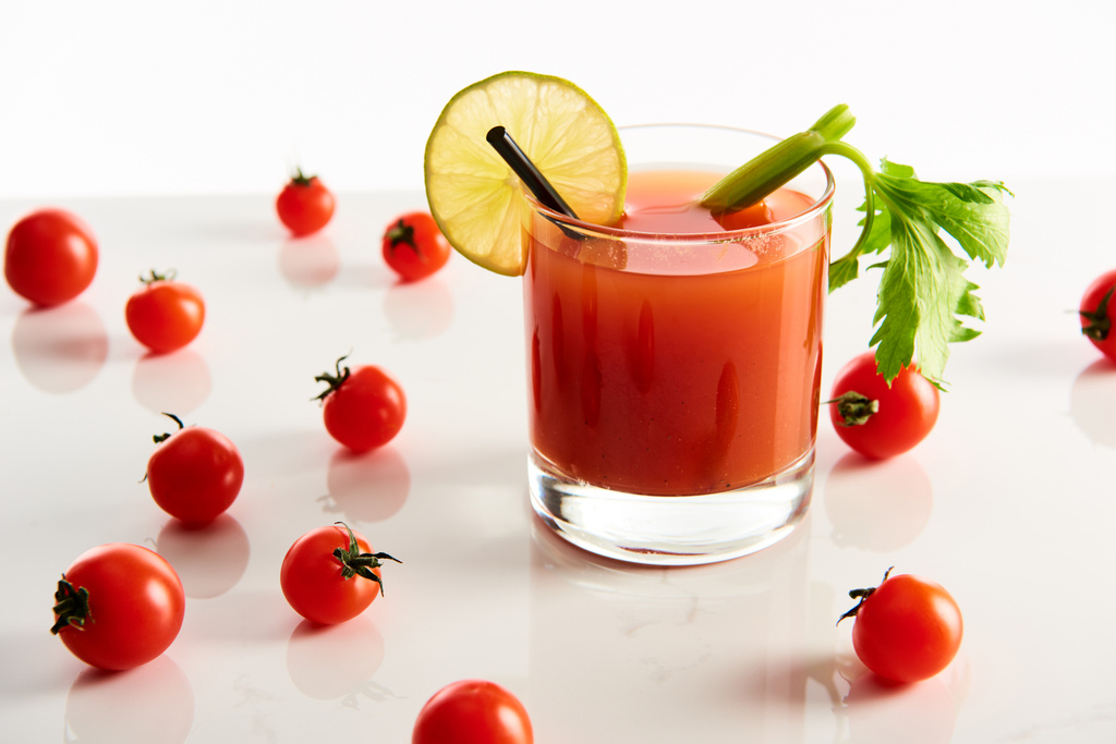 bloody mary cocktail in glass garnished with lime and celery isolated on white with tomatoes - Photo, Image