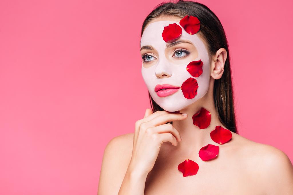 гола красива жінка в масці для обличчя з пелюстками троянд ізольована на рожевому
  - Фото, зображення