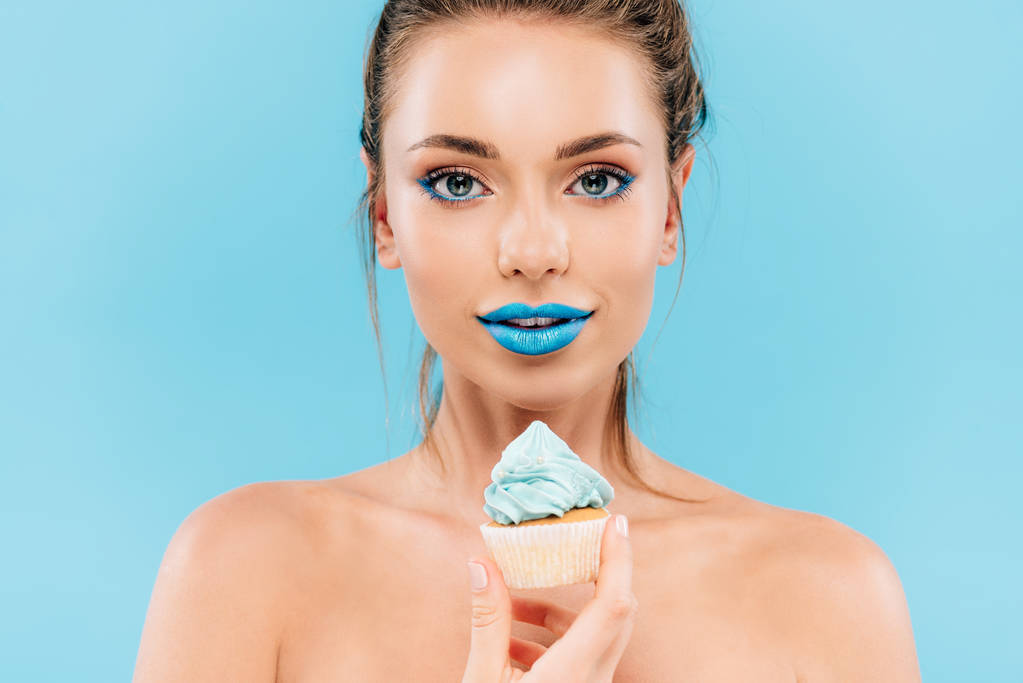 mulher bonita nua com lábios azuis e cupcake isolado em azul
 - Foto, Imagem
