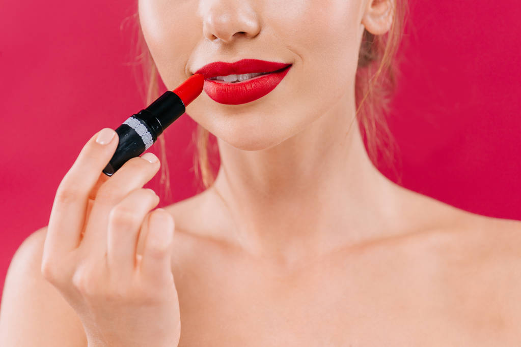 vista cortada de mulher bonita nua com lábios vermelhos aplicando batom isolado no carmesim
 - Foto, Imagem