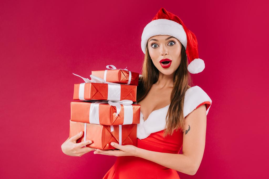 shocked sexy beautiful santa girl holding gift boxes isolated on burgundy - Photo, Image