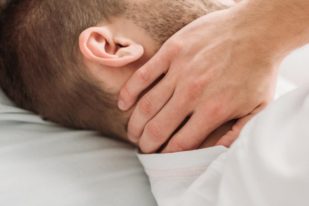 Ausgeschnittener Blick auf jungen Mann, der vor Schmerzen den Hals berührt - Foto, Bild