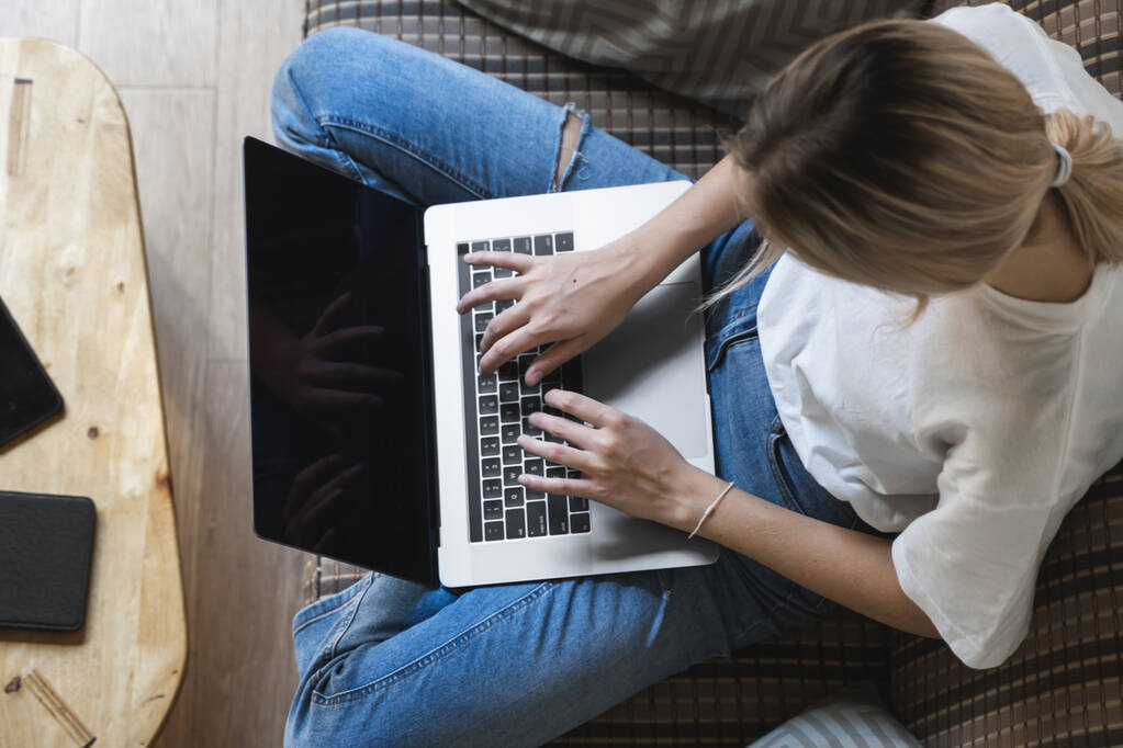 Egy nő laptoppal a kanapén. Online tanulás és munka, szabadúszó. Önálló vállalkozó nő, lány dolgozik a notebook ül a kanapén egy telefon, okostelefon és olvasó az asztalon. - Fotó, kép