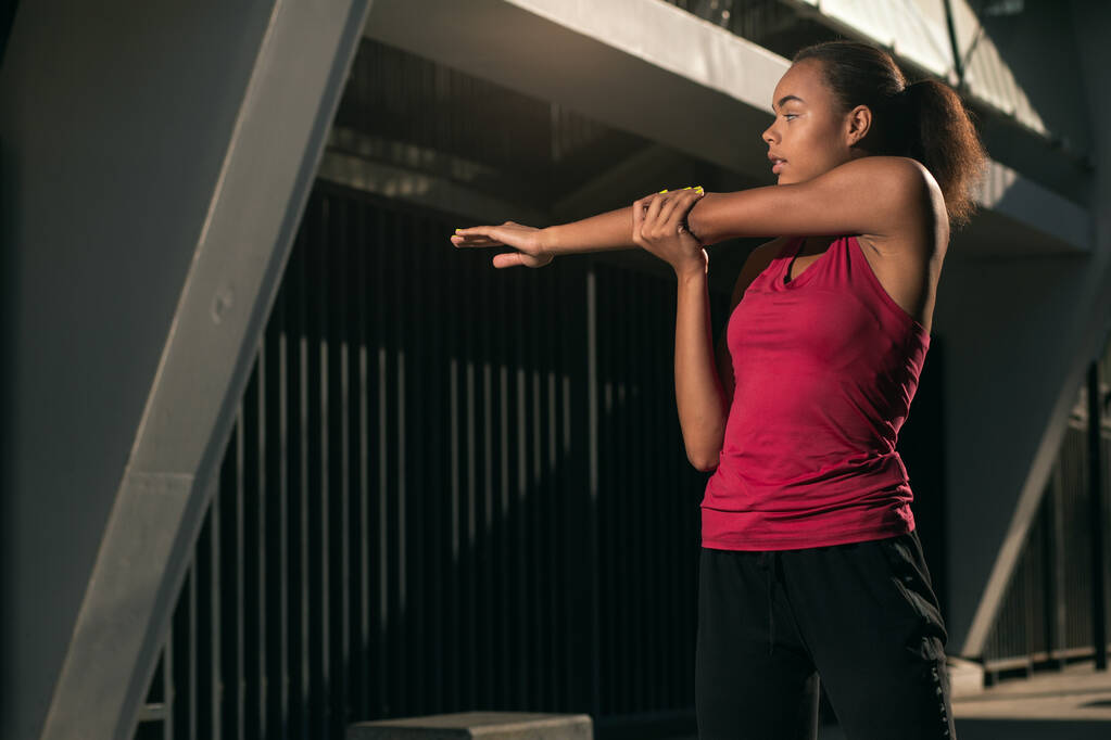 Kalm zelfverzekerde atleet trekken haar arm tijdens het opwarmen van de schouder spieren - Foto, afbeelding
