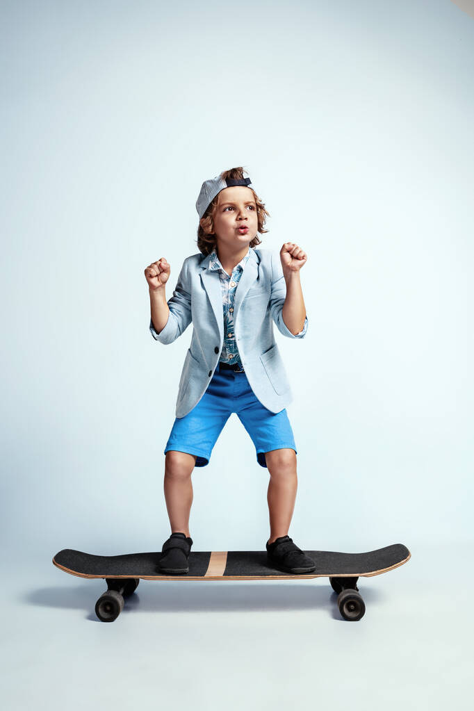 Joli jeune garçon sur skateboard en vêtements décontractés sur fond de studio blanc
 - Photo, image