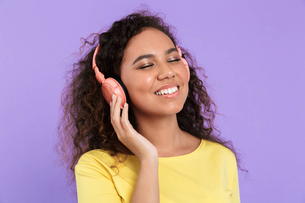 ヘッドフォンで音楽を聴く楽しいアフリカ系アメリカ人女性のイメージ - 写真・画像