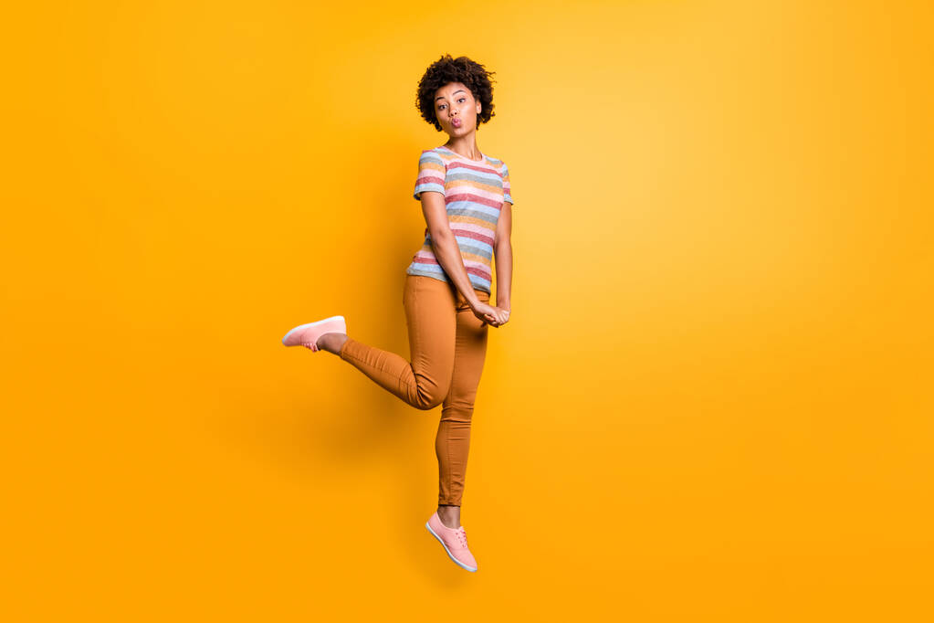 Full length profile photo of jumping high dark skin wavy lady sending coquettish air kisses wear casual summer clothes isolated bright yellow color background - Photo, Image