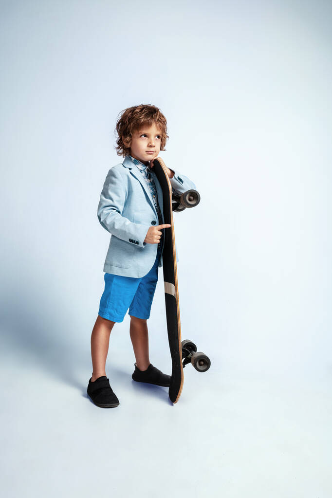 Csinos fiatal fiú gördeszka alkalmi ruhák fehér stúdió háttér - Fotó, kép