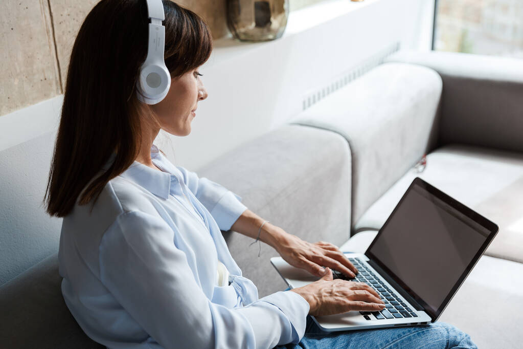 Mujer dentro de casa escuchando música con auriculares
 - Foto, imagen
