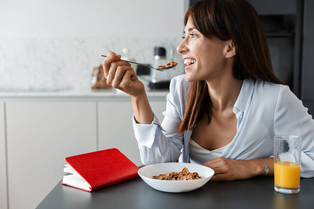 Pozytywny optymistyczny wesoły kobieta wewnątrz w domu w kuchni zjeść śniadanie płatki kukurydziane. - Zdjęcie, obraz
