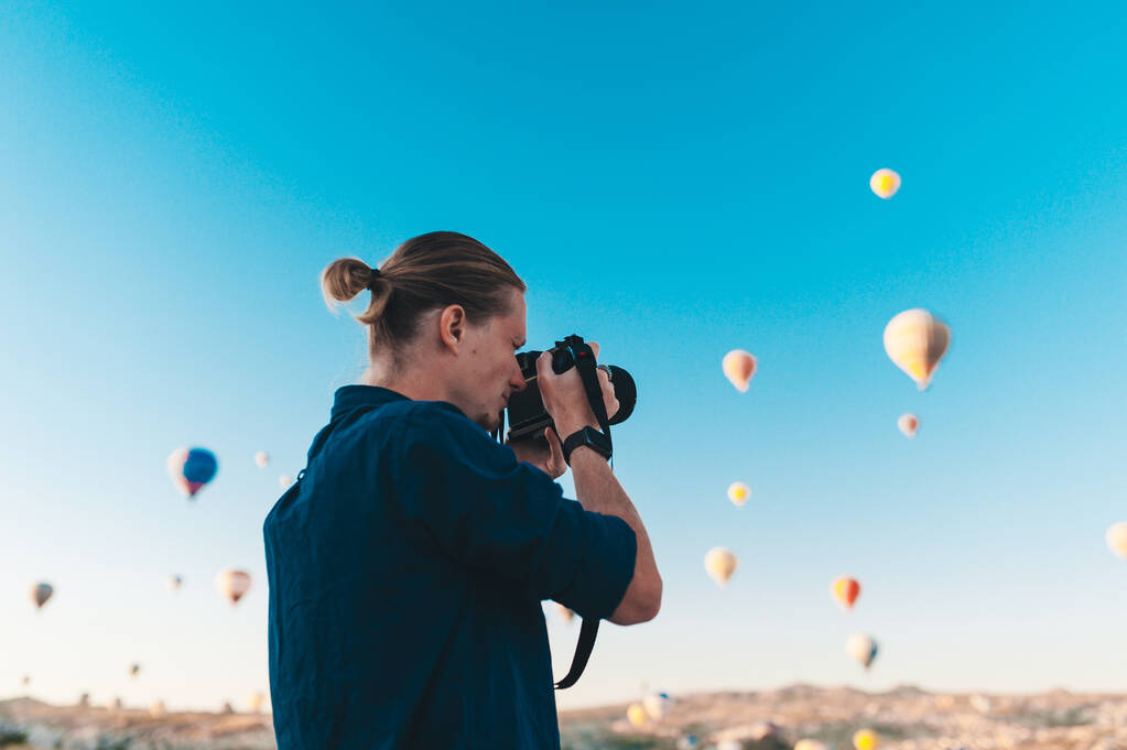 Nuori mies valokuvaaja tekee kuvia ilmapalloja auringonnousun aikaan Cappadocia
 - Valokuva, kuva
