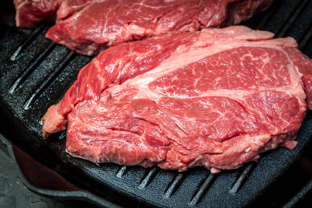 Un steak de bœuf marbré cru est assis dans une poêle
. - Photo, image