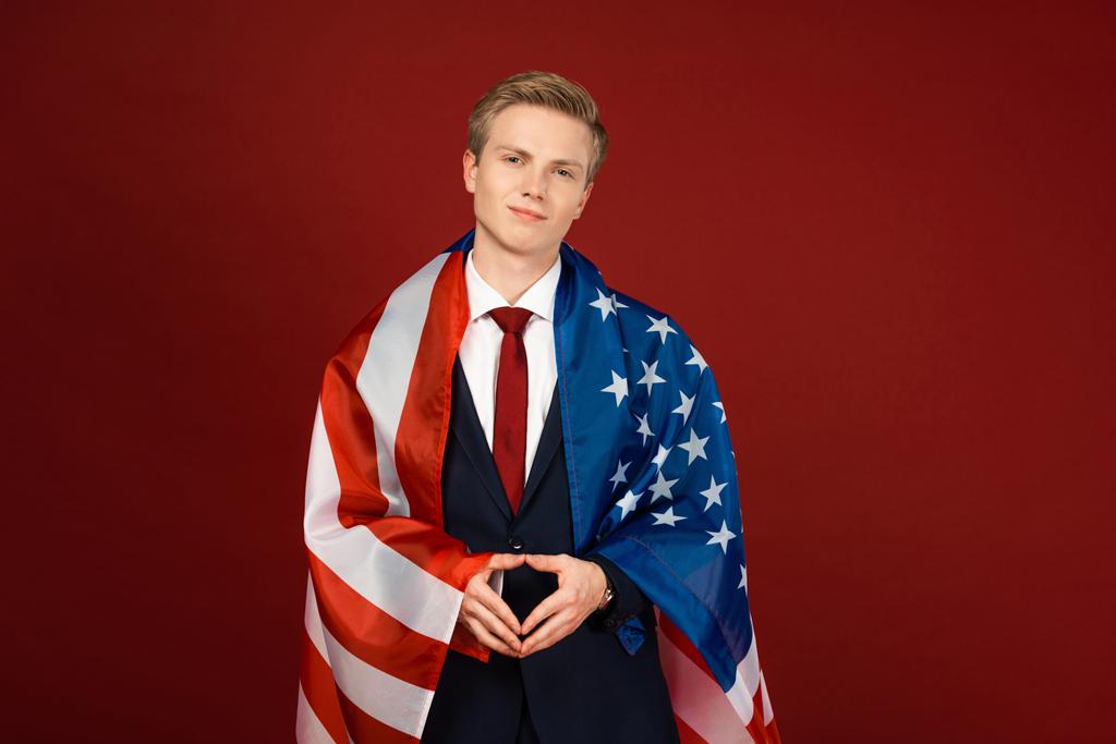 Lächelnder Mann mit amerikanischer Flagge auf rotem Hintergrund - Foto, Bild