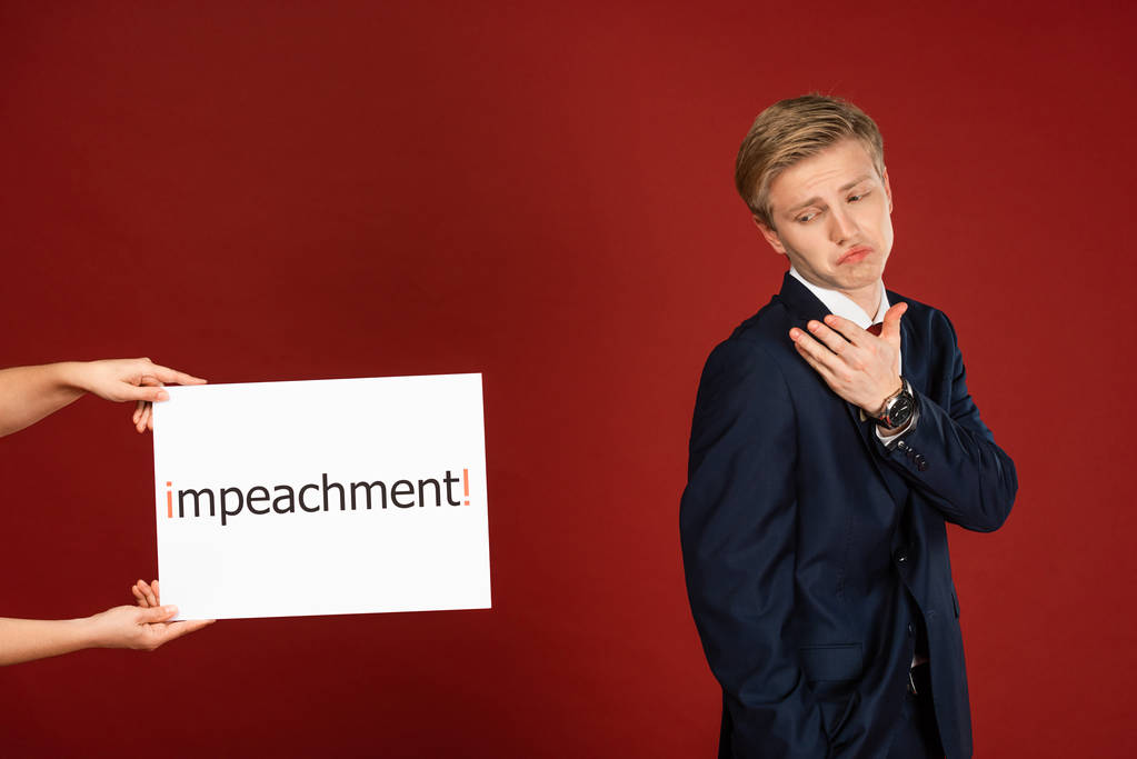 skeptical man near white card with impeachment lettering on red background - Photo, Image