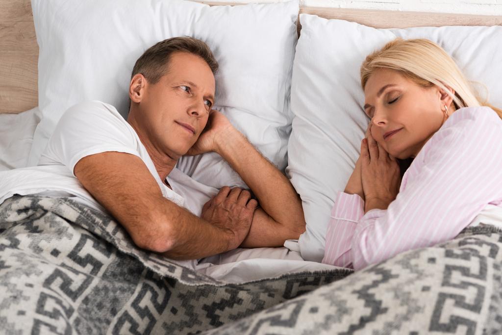 man kijkt naar slapende vrouw in bed  - Foto, afbeelding