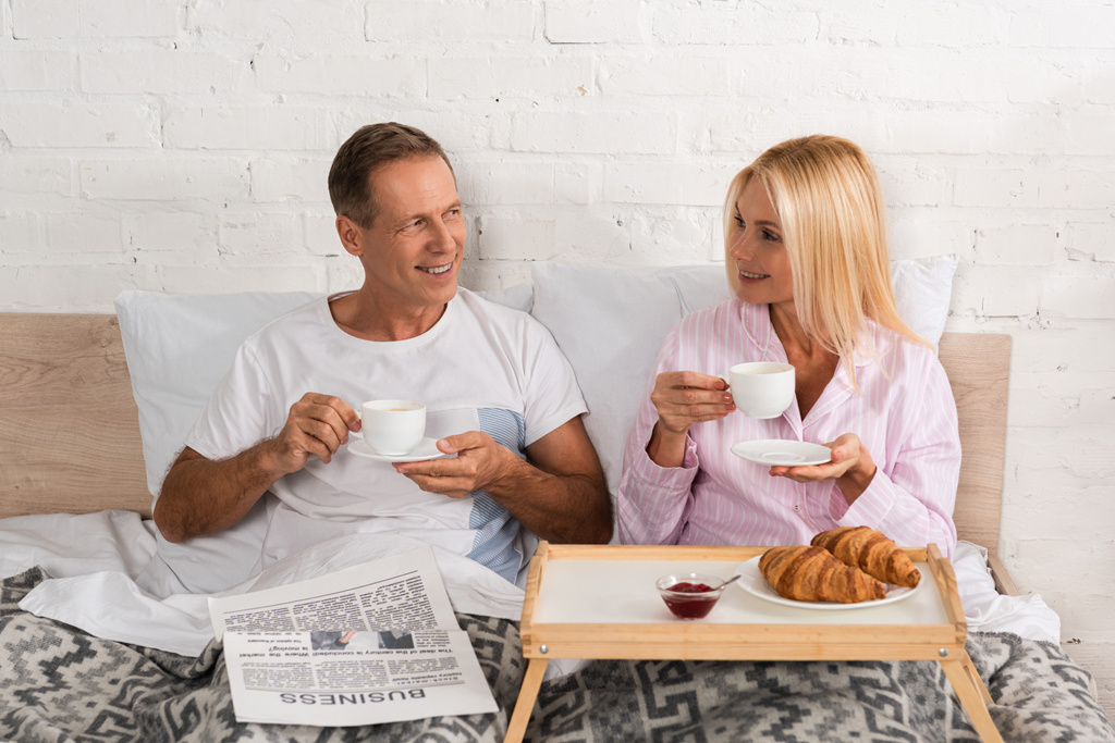 Usmívající se starší pár s novinami se snídaní v posteli - Fotografie, Obrázek