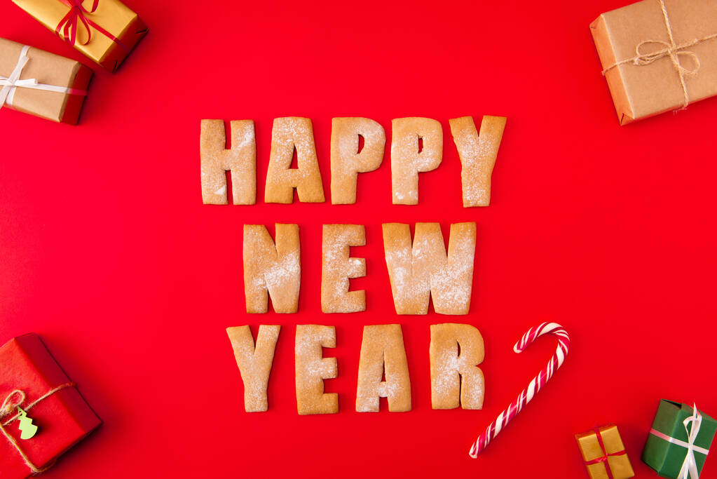 Hoge hoek boven uitzicht foto van verrassing nieuwjaar koekjes gefeliciteerd woorden decor figuren smakelijk lekker x-mas samenstelling giftboxen snoep geïsoleerd helder rood achtergrond - Foto, afbeelding