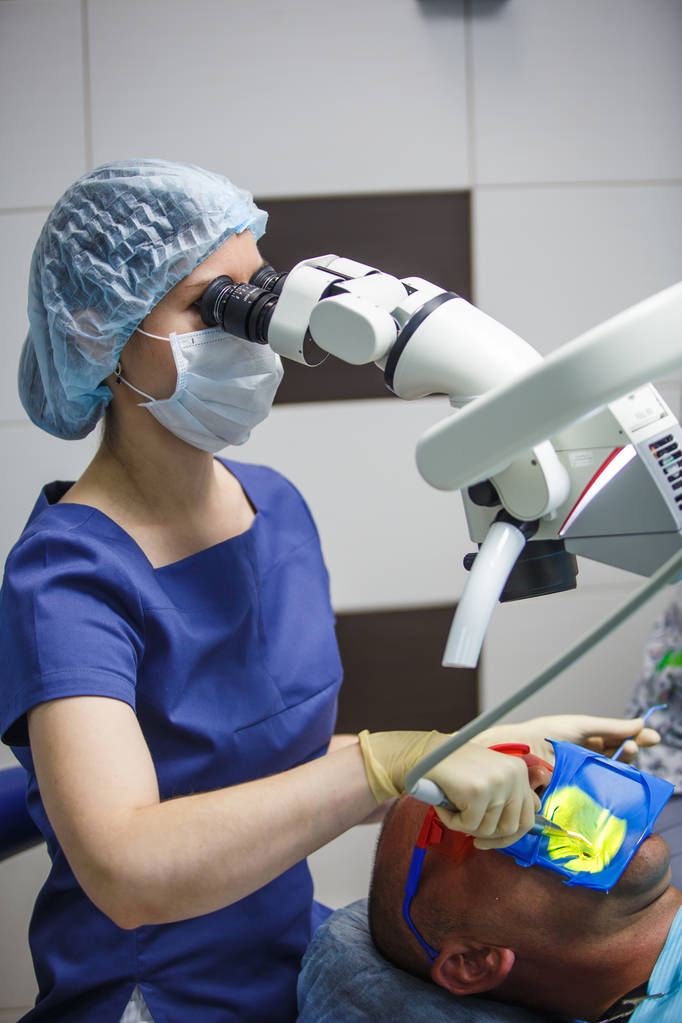 Naishammaslääkäri tutkii mikroskooppia. Potilaan hoito mikroskoopilla hammashoitolassa
 - Valokuva, kuva