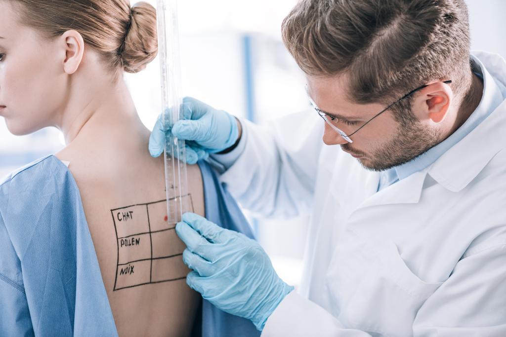 vousatý alergik drží pravítko v blízkosti pacienta se značenými zády  - Fotografie, Obrázek