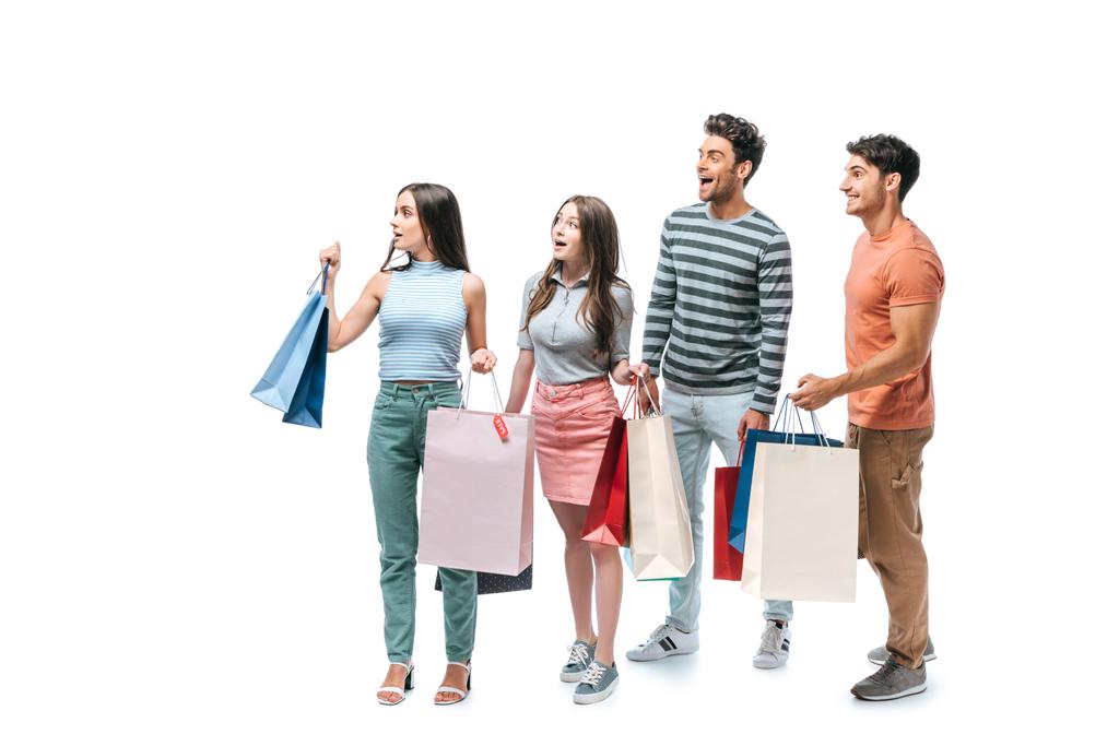 amigos sorprendidos caminando con bolsas de compras juntos, aislados en blanco
 - Foto, imagen