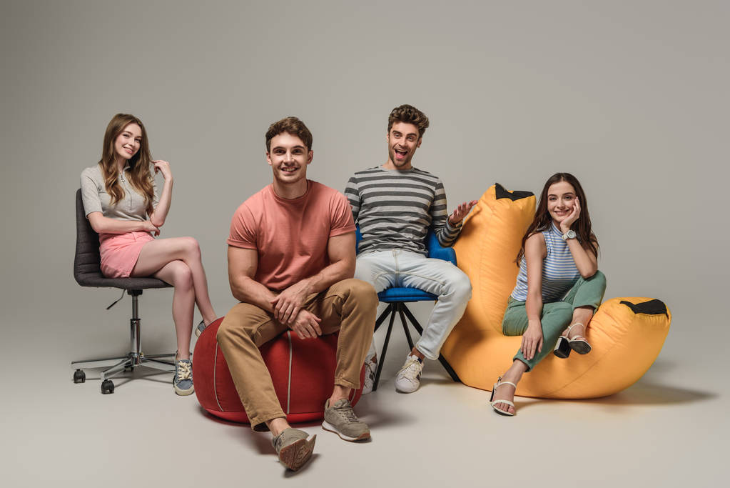 Счастливые друзья сидят на разных стульях, на сером
 - Фото, изображение
