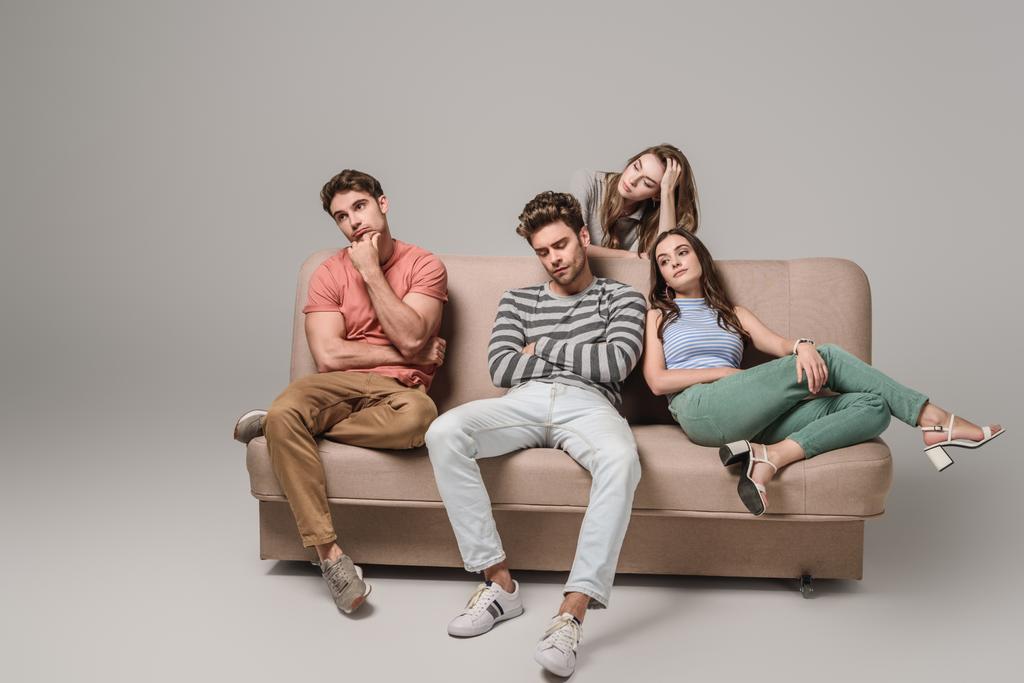 znuděný a zamyšlený přátelé sedí spolu na pohovce na šedé  - Fotografie, Obrázek