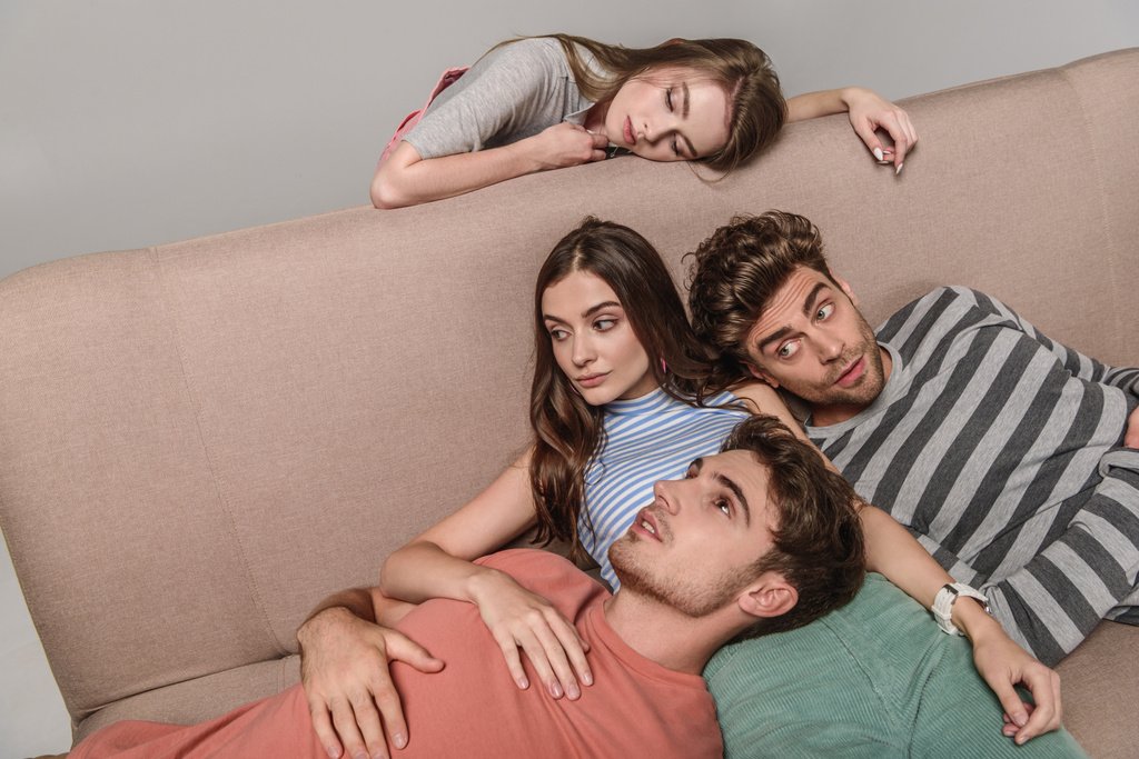gelangweilte junge Freunde liegen zusammen auf dem Sofa isoliert auf grau  - Foto, Bild