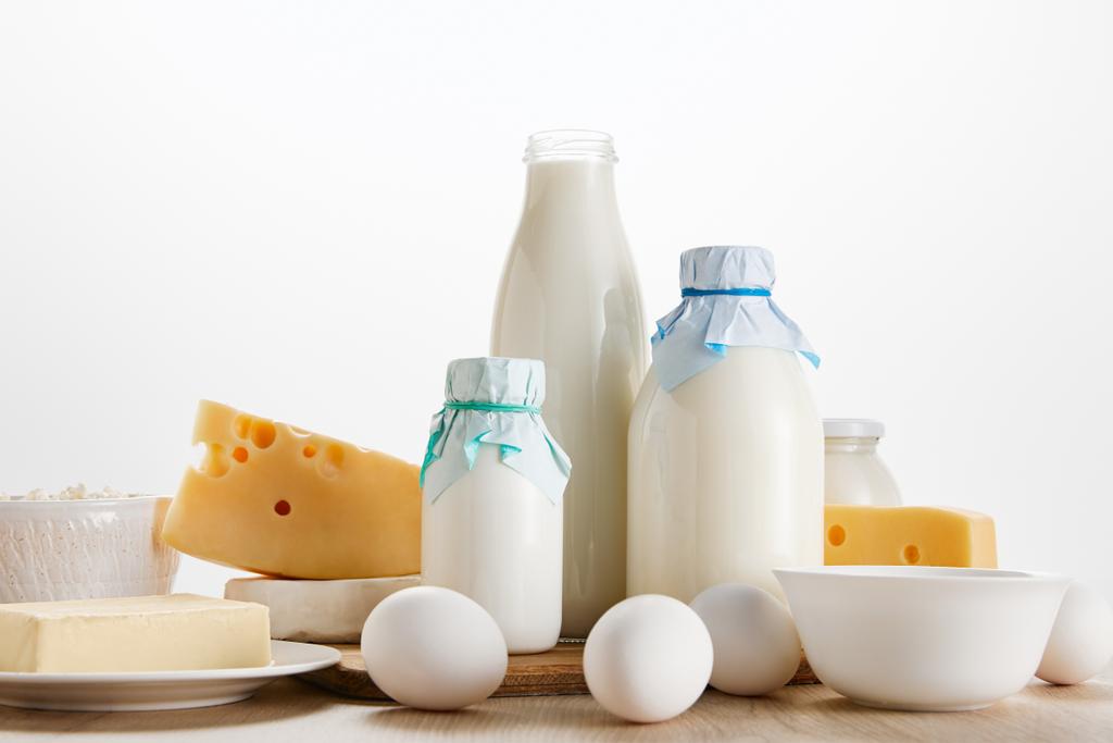 vários produtos lácteos orgânicos frescos e ovos em mesa de madeira isolada em branco
 - Foto, Imagem