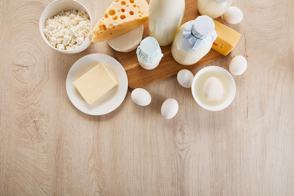 pohled shora na různé čerstvé organické mléčné výrobky a vejce na dřevěném stole - Fotografie, Obrázek