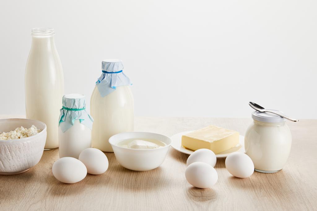 pyszne ekologiczne przetwory mleczne i jaja na drewnianym stole izolowane na białym - Zdjęcie, obraz