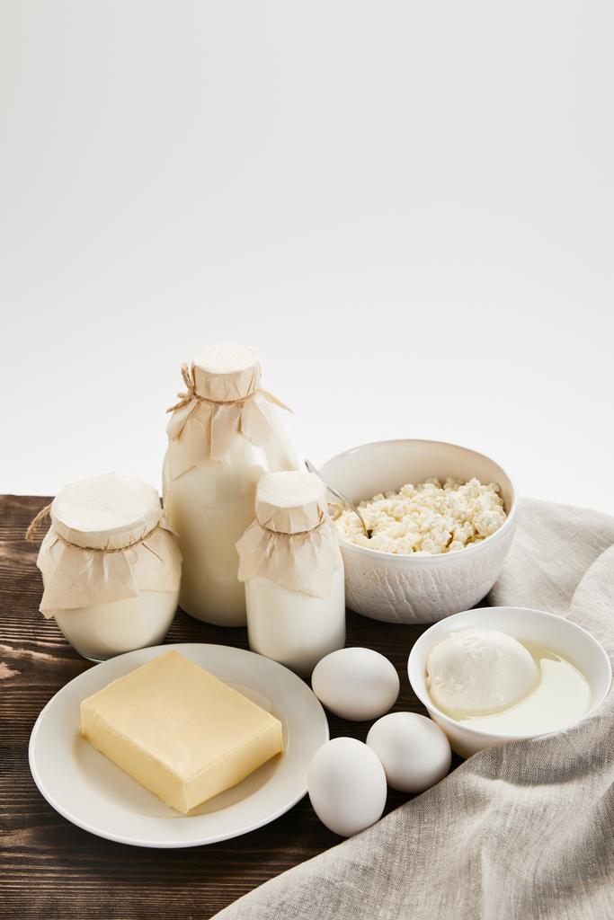 Lezzetli taze süt ürünleri ve kırsal ahşap masa üzerinde yumurtalar ve beyaz üzerine izole edilmiş kumaş. - Fotoğraf, Görsel
