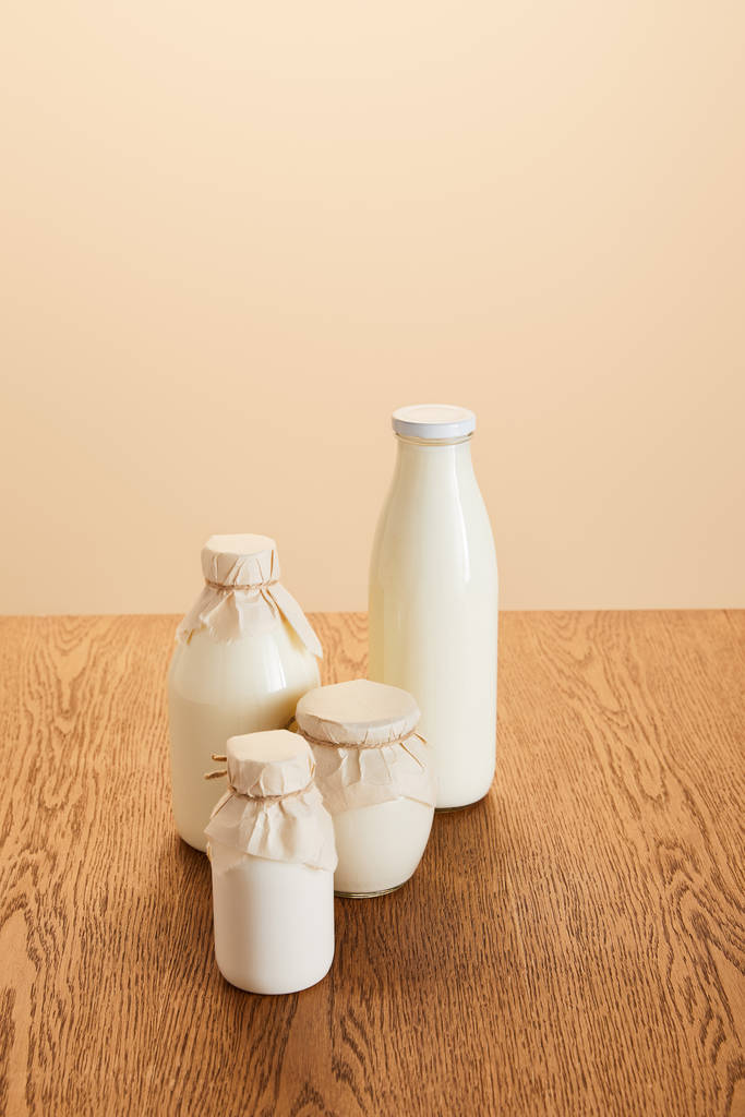savoureux produits laitiers bio en bouteilles sur table rustique en bois isolé sur beige
 - Photo, image