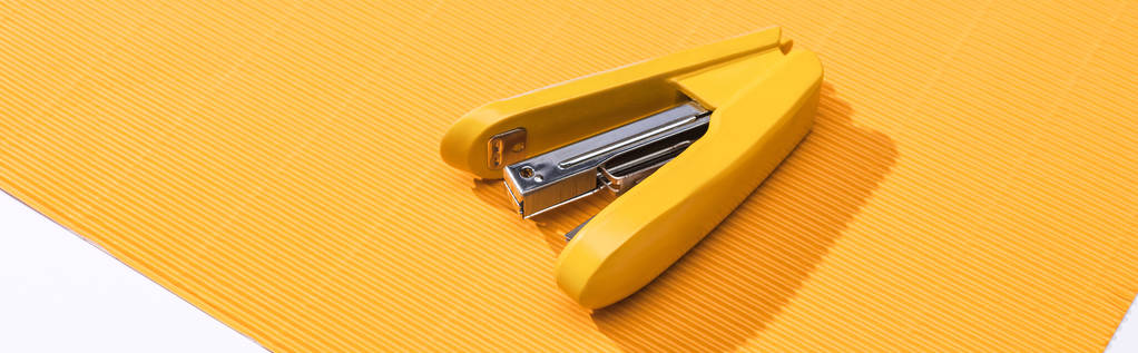 panoramic shot of yellow stapler on bright paper isolated on white  - 写真・画像