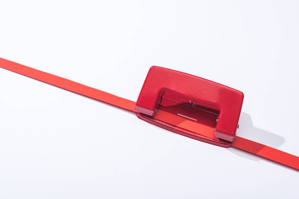 high angle view of red holepunch and paper strip on white background  - Photo, Image