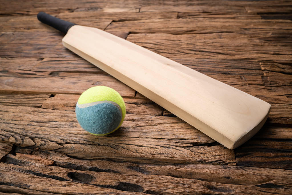 Primo piano di cricket pipistrello e palla su sfondo strutturato in legno
 - Foto, immagini