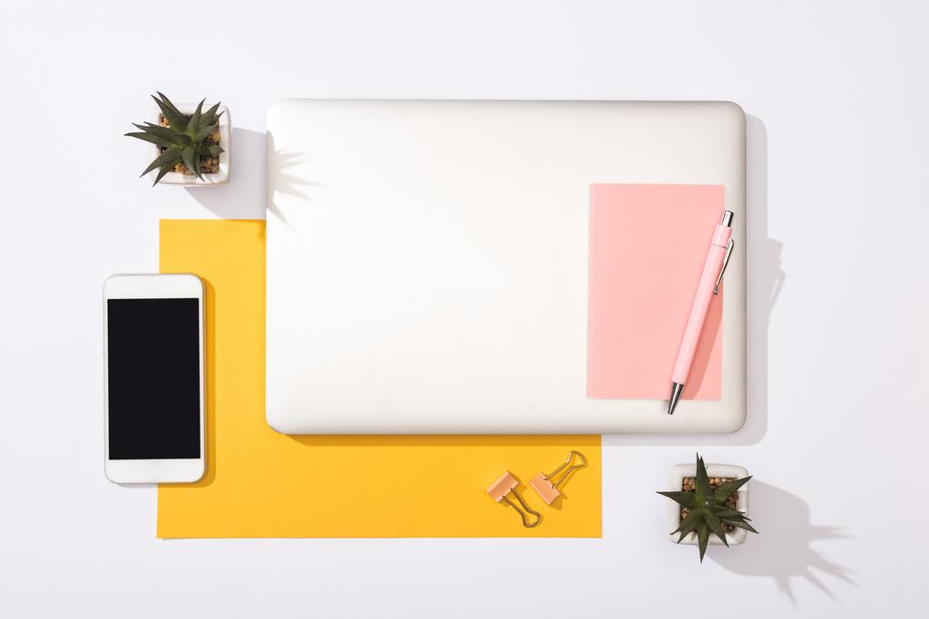 vista superior de laptop, plantas, papel amarelo, notebook, caneta, smartphone, clipes de aglutinante
   - Foto, Imagem