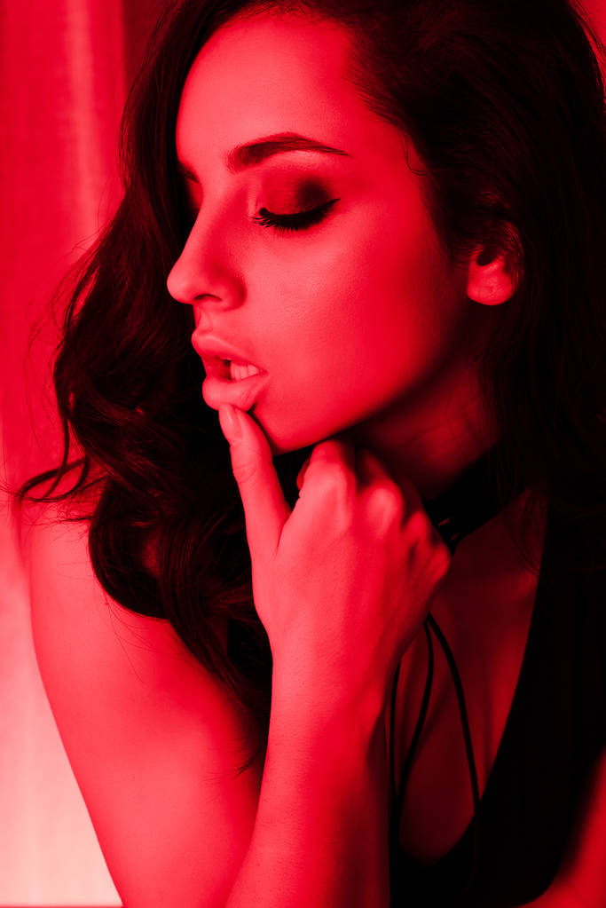 hermosa chica apasionada posando en traje de cuerpo en luz roja
 - Foto, imagen