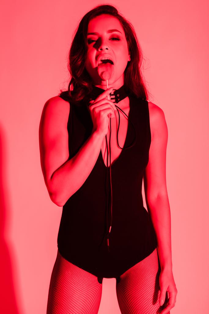 beautiful sexy woman eating lollipop in red light - Photo, Image