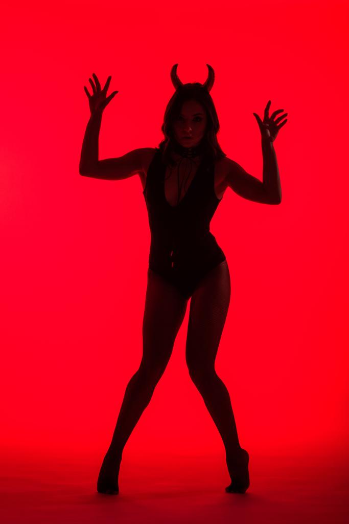 silhouette di bella giovane donna in costume Devil, isolata su rosso
 - Foto, immagini