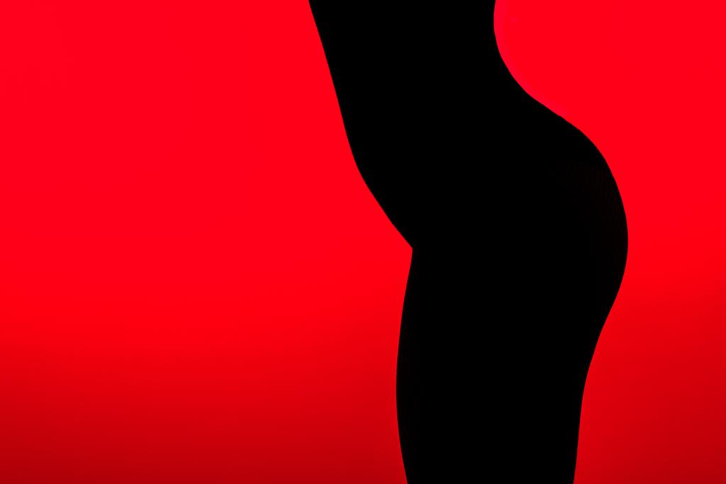 赤に隔離された若い女性のセクシーなお尻の黒いシルエット - 写真・画像