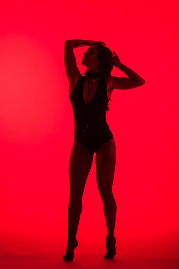 σιλουέτα της όμορφης σέξι νεαρή γυναίκα, απομονωμένη σε κόκκινο - Φωτογραφία, εικόνα