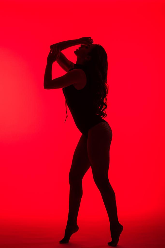 σιλουέτα του όμορφου παθιασμένου κοριτσιού, απομονωμένη σε κόκκινο - Φωτογραφία, εικόνα