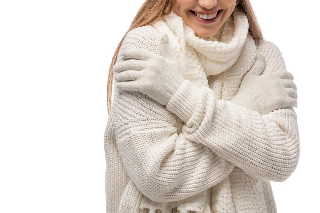 oříznutý pohled usměvavé ženy zahřívající se v bílých pletených šatech, izolované na bílém - Fotografie, Obrázek