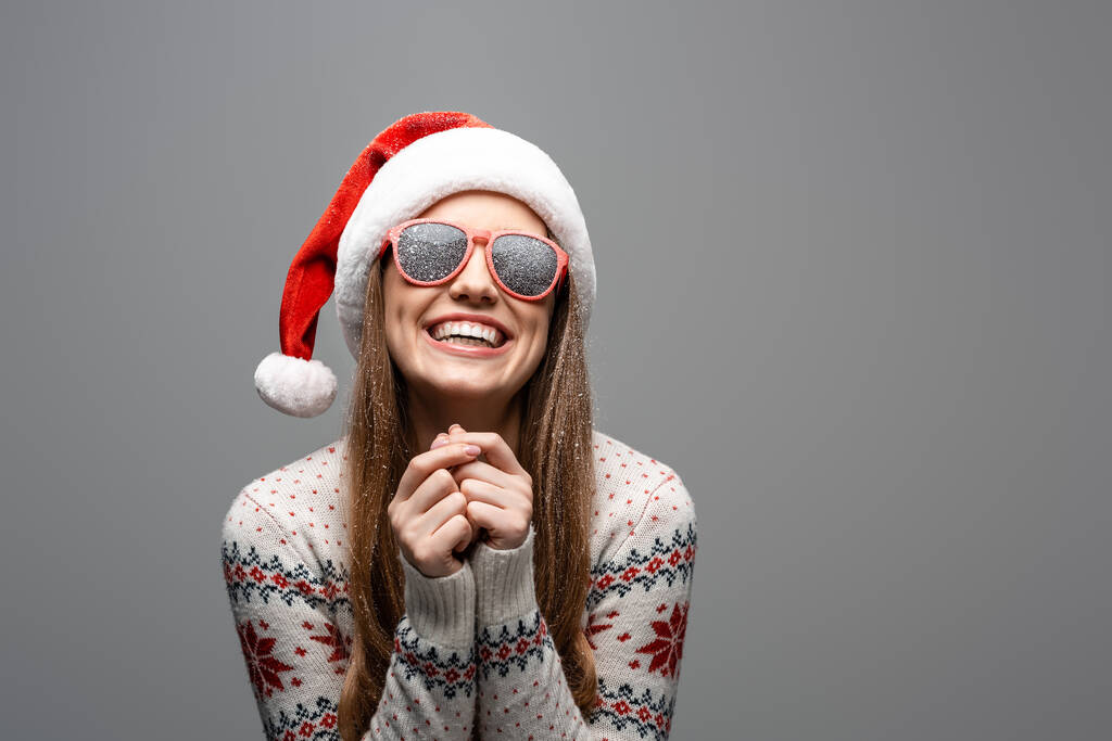 bella donna sorridente in maglione di Natale, cappello di Babbo Natale e occhiali da sole, isolata su grigio
 - Foto, immagini